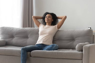 Happy black girl relaxing on comfortable couch at home clipart