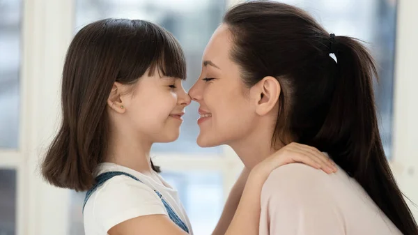 Cheerful young mother touching noses with adorable daughter. — Stock Photo, Image