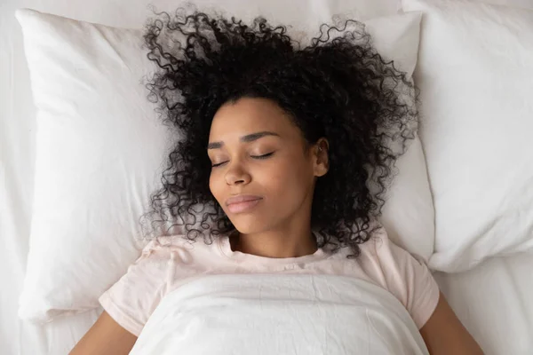 Вид сверху на бирасовую девочку, спящую на мягкой белой подушке — стоковое фото