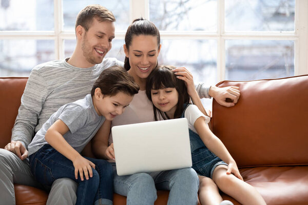 Joyful family sitting on couch, looking at laptop screen.