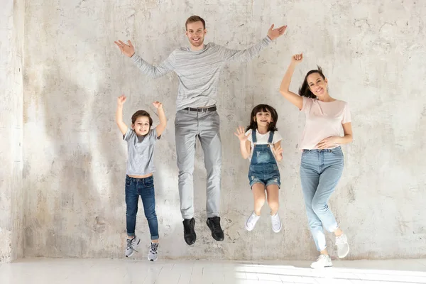Full length overjoyed young parents jumping with little kids siblings. — Stock Photo, Image