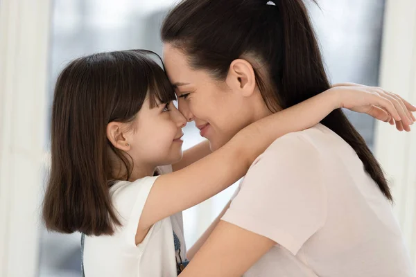 Cute little daughter touching foreheads with mother. — Stock Photo, Image