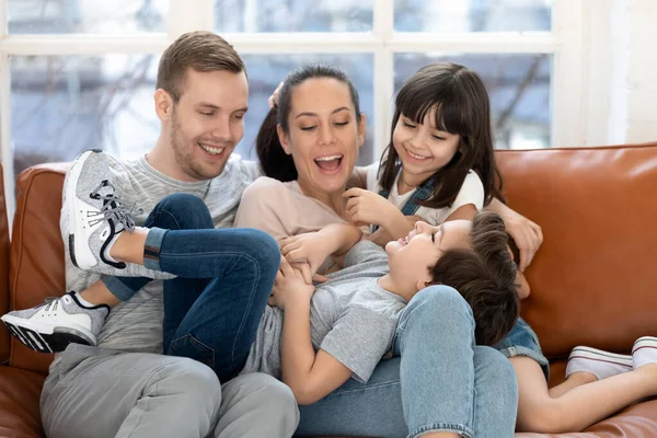 Overjoyed parents and smiling daughter tickling laughing son brother. — Stock Photo, Image
