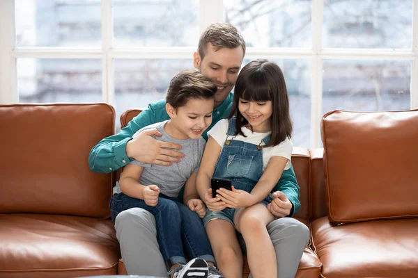 Vreugdevolle vader houdt twee kleine kinderen dochter zoon op de knieën. — Stockfoto
