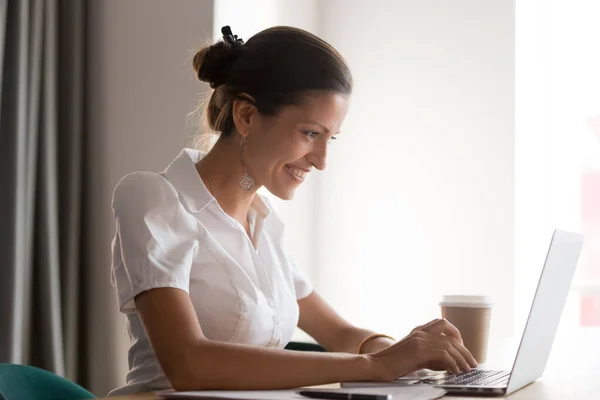 Улыбающаяся молодая деловая женщина, работающая за компьютером в офисе . — стоковое фото