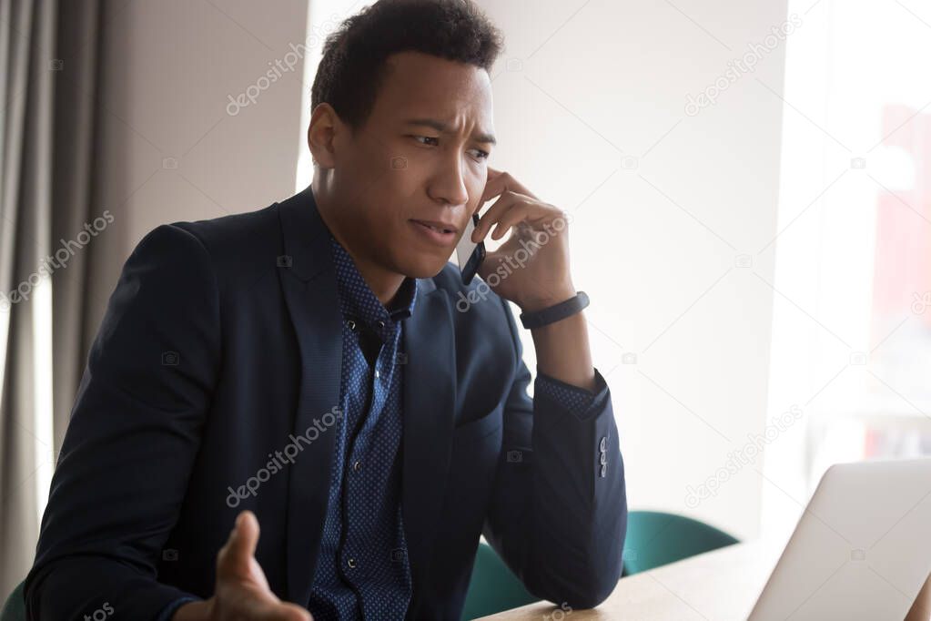 Angry black businessman disputing on phone at office