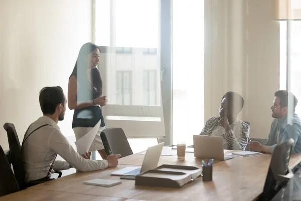 Asian businesswoman holding briefing with diverse colleagues behind glass — Stock Photo, Image