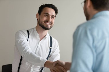 Smiling confident businessman shaking hand of business partner at meeting