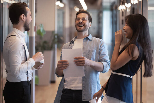 Happy diverse employees having fun in hallway during break