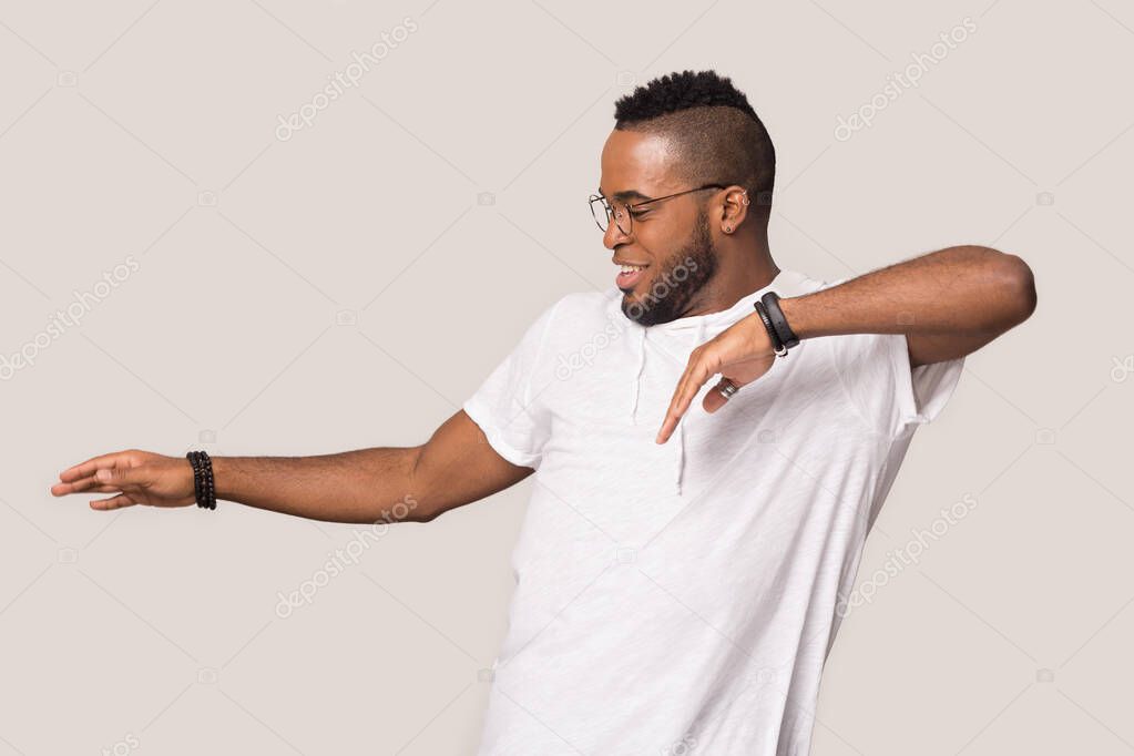 Overjoyed african American man dancing in grey studio