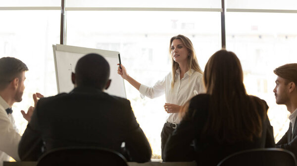 Confident female speaker making whiteboard presentation to employees