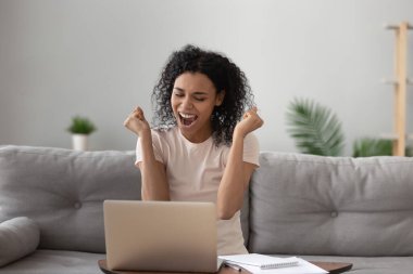 Mutlu Afrikalı Amerikalı kadın, bilgisayarını kullanarak başarıdan heyecan duyuyor.