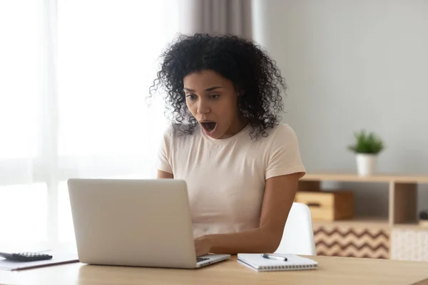 Mujer afroamericana conmocionada con la boca abierta usando el ordenador portátil — Foto de Stock