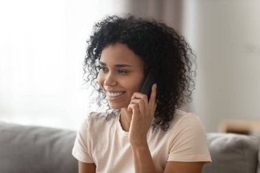 Gülümseyen Afrikalı Amerikalı kadın telefonda konuşuyor, arkadaşlarıyla sohbet ediyor.