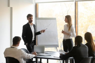 Koç çalışma grubu için flip çizelgesi sunumu yapıyor