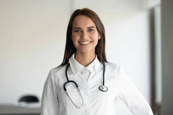 Retrato de mulher sorridente médico posando vestindo brancos — Fotografia de Stock