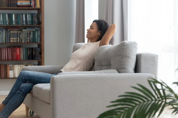 Calma sorrindo mulher afro-americana relaxando no sofá em casa — Fotografia de Stock