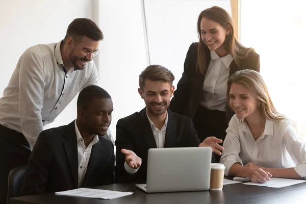 Diversi dipendenti sorridenti che cooperano in ufficio utilizzando il computer portatile — Foto Stock