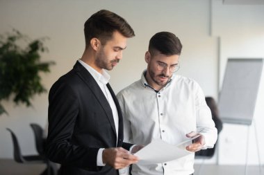 Düşünceli erkek meslektaşlar ofiste evrak istatistiklerini değerlendiriyor