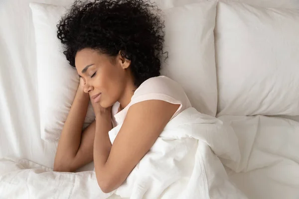 Wanita Afrika-Amerika dengan tangan di bawah pipi tidur di tempat tidur — Stok Foto