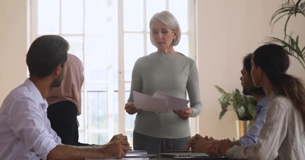 Une femme plus âgée présente un nouveau plan de marketing lors d'un briefing de groupe — Video