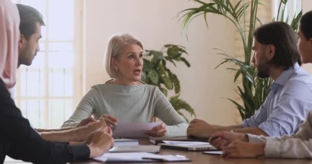 Ernstige oudere vrouwelijke leider in gesprek met team mensen bespreken van papierwerk — Stockvideo