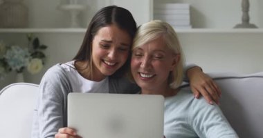 Evde dizüstü bilgisayar kullanan mutlu bir anne ve yetişkin kız.