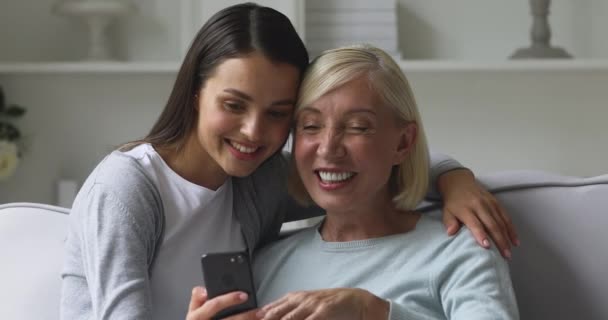 Happy mature mom and adult daughter having fun using phone — Stock Video