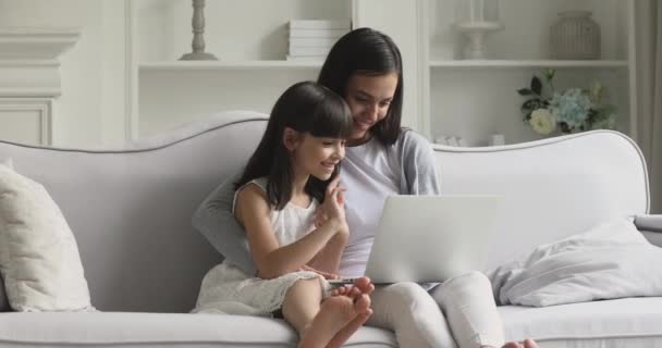 Feliz mamá y linda hija niño usando el ordenador portátil de compras en línea — Vídeo de stock