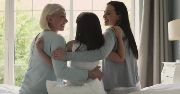 Счастливые три поколения многовозрастные женщины обнимают сидеть на кровати — стоковое видео