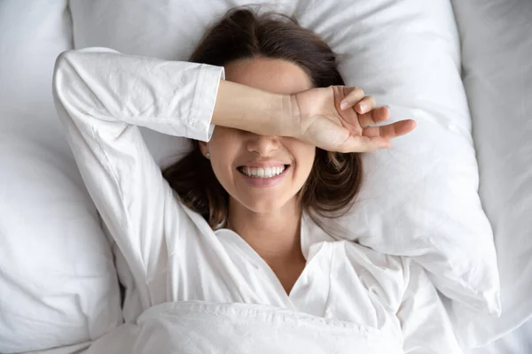 Усміхнена грайлива молода приваблива жінка лежить прокидається в зручному ліжку — стокове фото