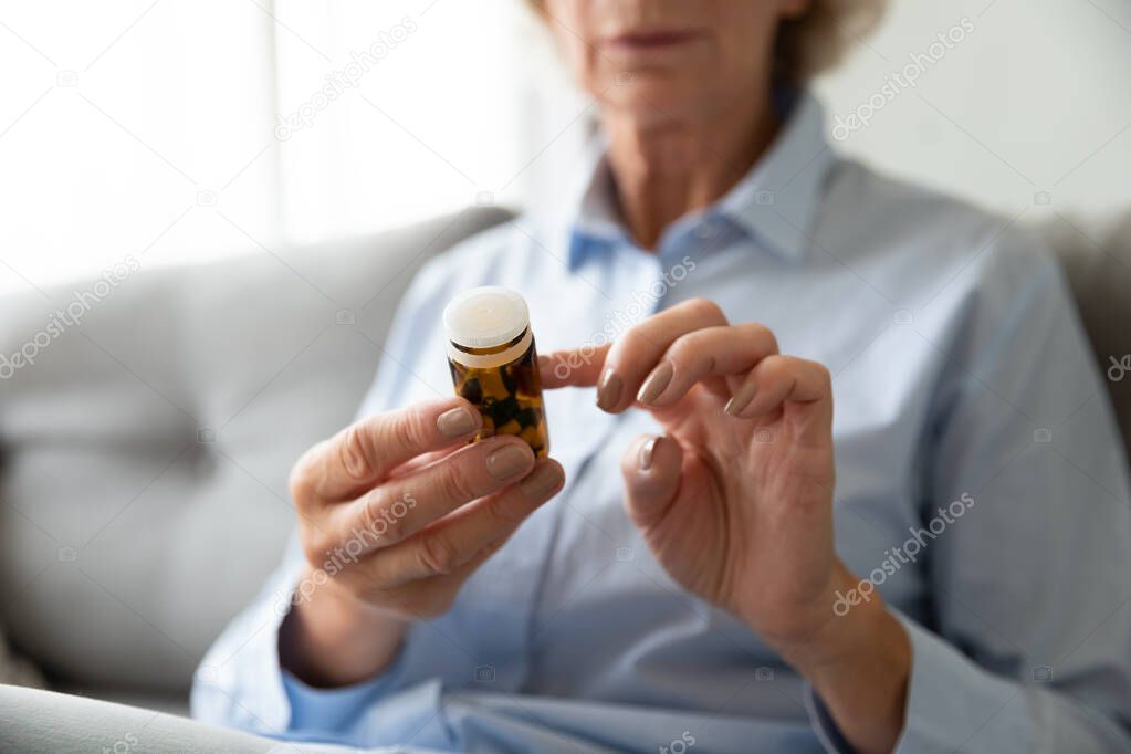 Senior woman hold pills bottle read medicine prescription, closeup view