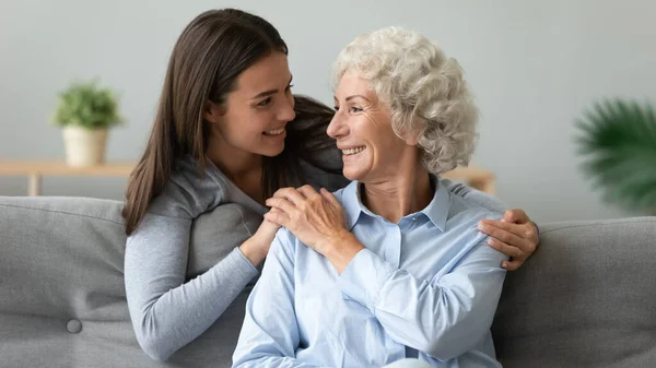 Cuidar jovem neta abraçar feliz velha avó em casa — Fotografia de Stock