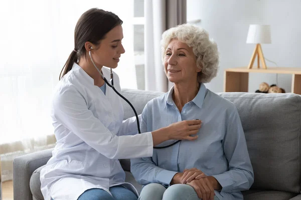Young woman doctor holding stethoscope examining senior grandma patient — Stock Photo, Image
