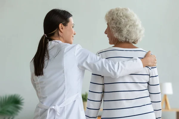 Giovane fisioterapista femminile aiuto ferito vecchia nonna paziente a piedi, fisioterapia — Foto Stock