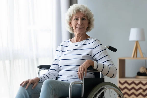 Feliz deficiente avó sênior sentar na cadeira de rodas olhando para a câmera — Fotografia de Stock