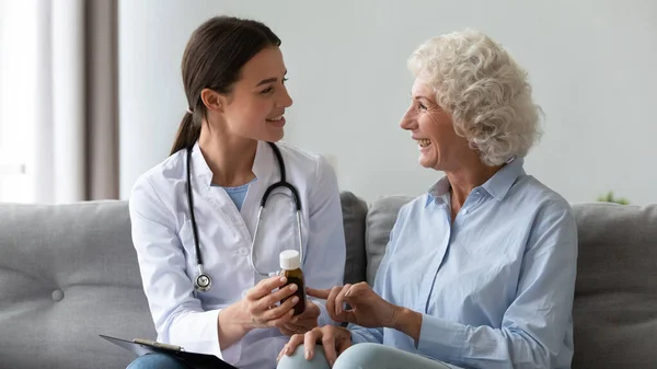 Smiling woman doctor prescribing medicine to happy senior grandmother patient — Stock Photo, Image