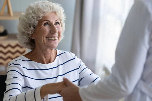 Happy grandma patient holding helping hand of caregiver getting up — Stock Photo, Image