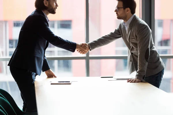 Sicuro serio due uomini d'affari che stringono la mano a ufficio . — Foto Stock