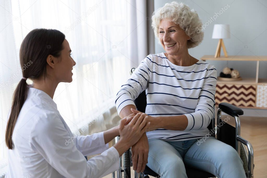 Caring female nurse support disabled elder woman patient on wheelchair