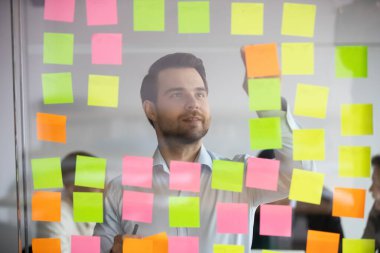 Genç profesyonel, Kanban yönetim kurulunda proje planlamakla meşgul..