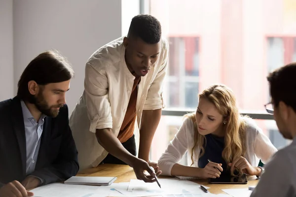 Concentrated african american young male employee explaining strategy to colleagues. — Stock Photo, Image