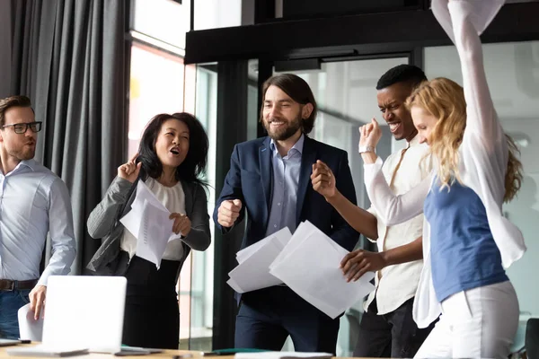 Overjoyed diverse coworkers celebrating corporate financial success.