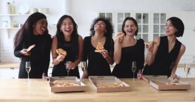 Mutlu kadın arkadaşlar şampanya içer, pizzayı mutfakta paylaşırlar.
