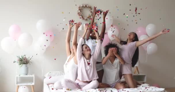 Carefree young diverse women celebrate pajama party throw confetti up — Stock Video