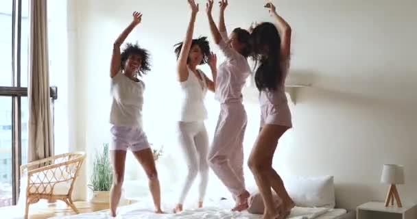 Carefree sexy diverse girlfriends jump on bed celebrate pajama party — Stock Video