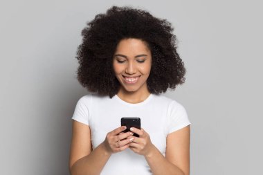 Gülümseyen Afrikalı Amerikalı kız telefon kullanıyor, sohbet ediyor ya da internetten alışveriş yapıyor.