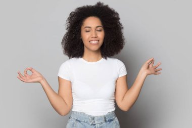 Sakin Afro-Amerikan kız gözleri kapalı meditasyon yapıyor.