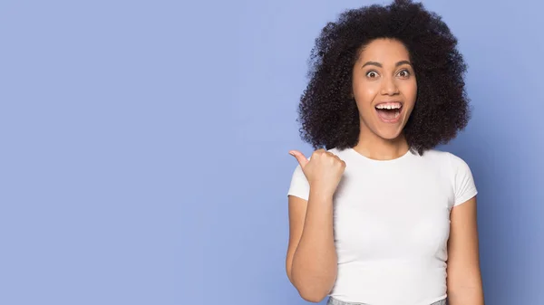 Excited surprised African American girl pointing finger to copy space — Stock Photo, Image