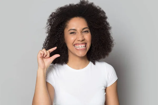 Head shot smiling African American girl showing little size gesture — Stock Photo, Image